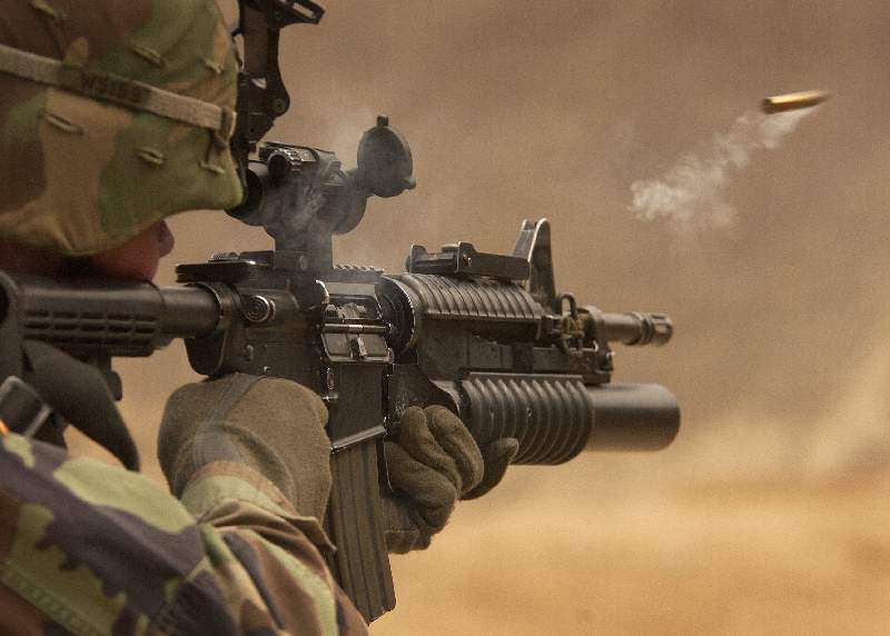 A soldier is holding an m 1 6 rifle in the desert.